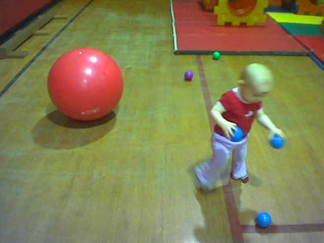 an infant playing ball in an indoor indoor playground