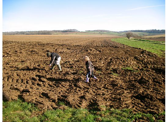 two people plow the fields in a large field