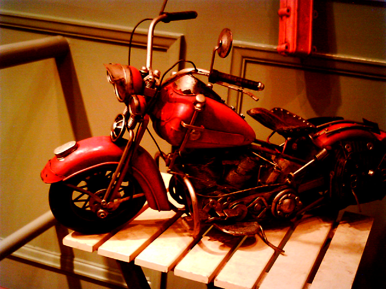 red motorcycle is displayed on wooden ledge in room