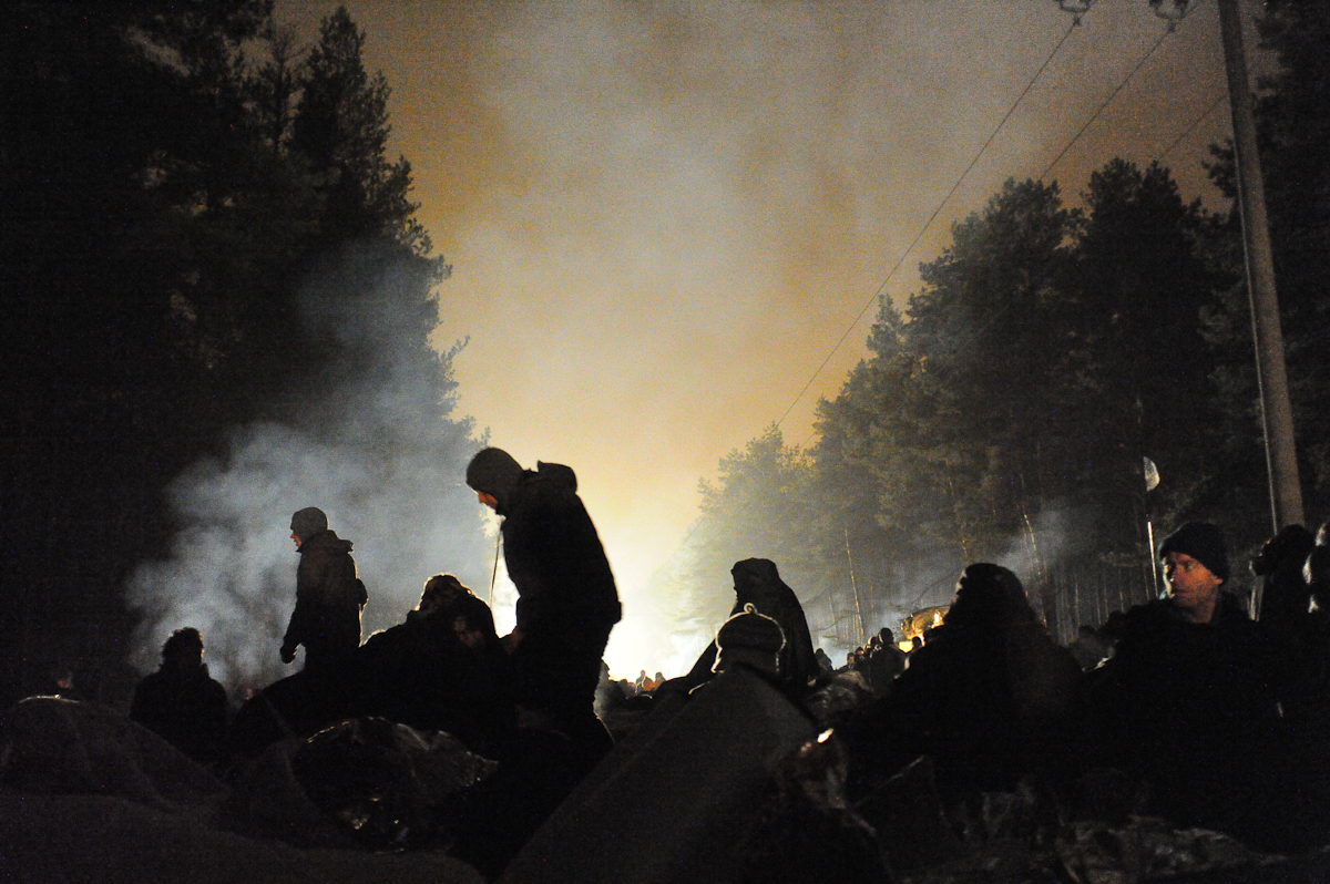 a group of people gather around a bonfire at night