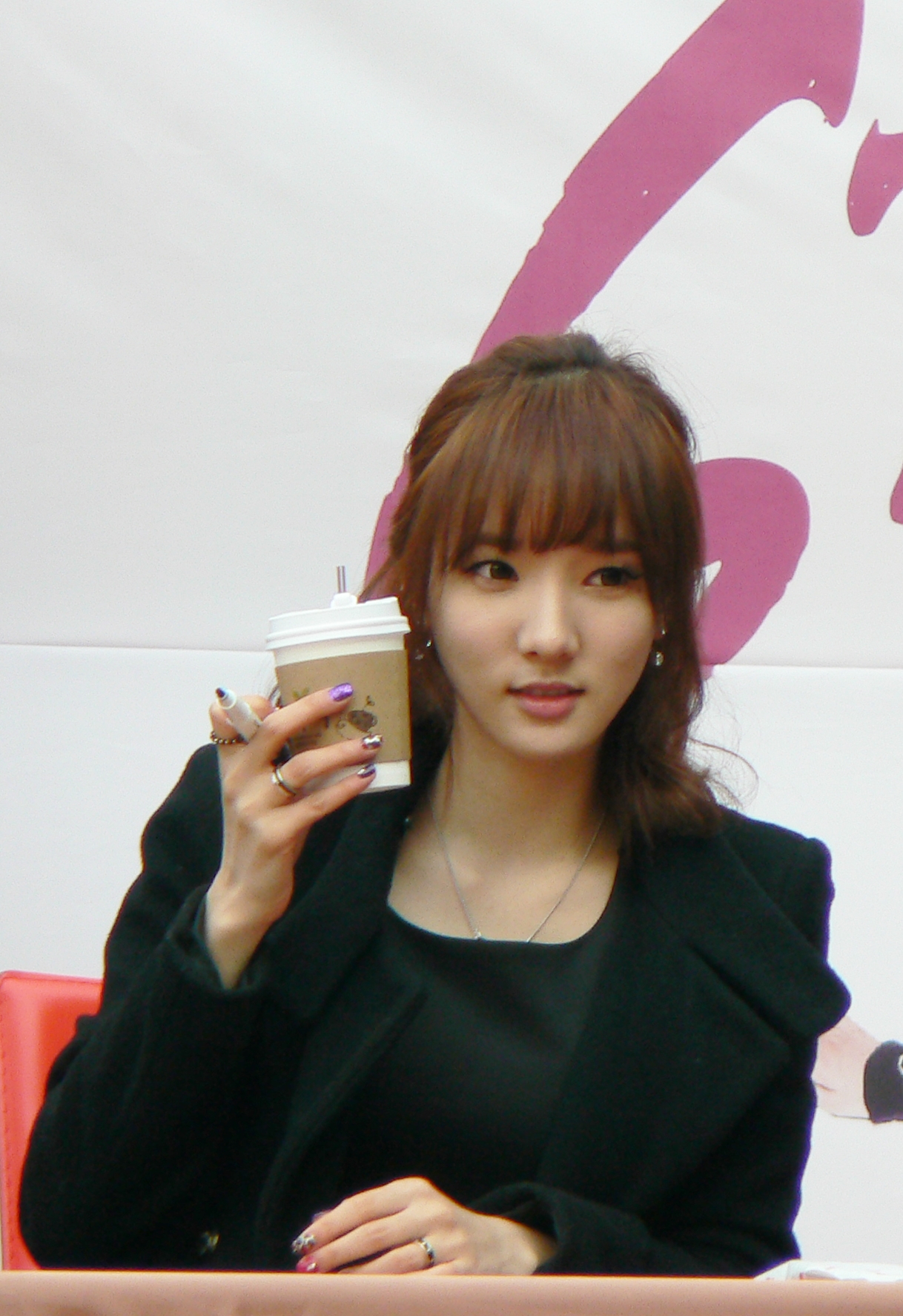 a woman with brown hair and a small cup