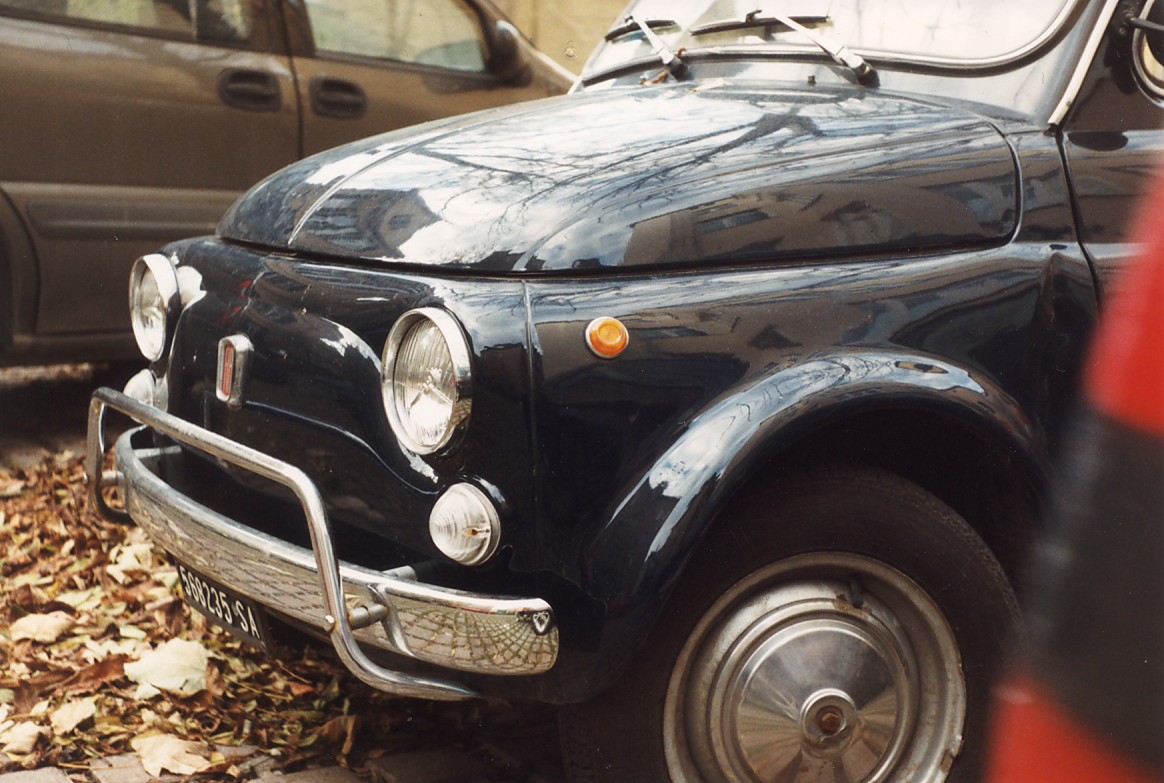 a small black and red car parked next to another car