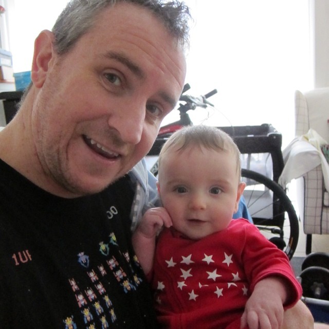 a man holding a baby with stars on his shirt