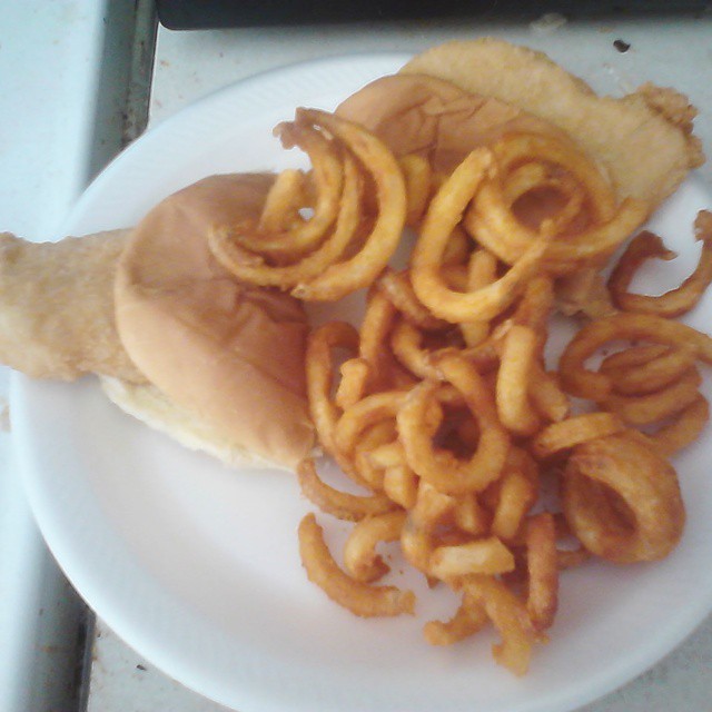 a white plate topped with onion rings and a burger