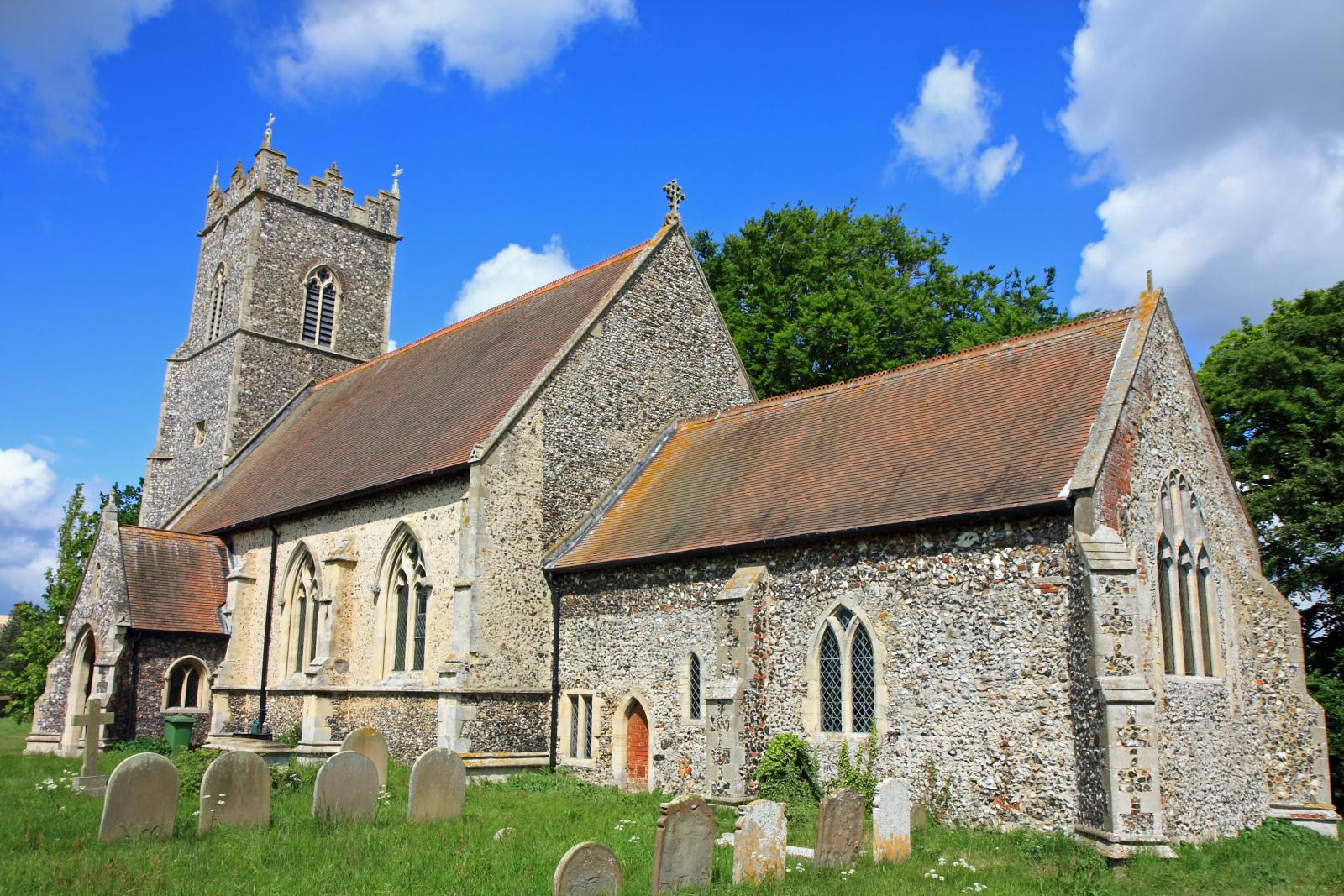 a stone church with a steeple, graves and trees