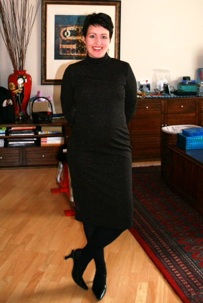 a woman wearing a black dress stands on a wooden floor