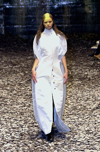 the woman walks down the runway in a white outfit