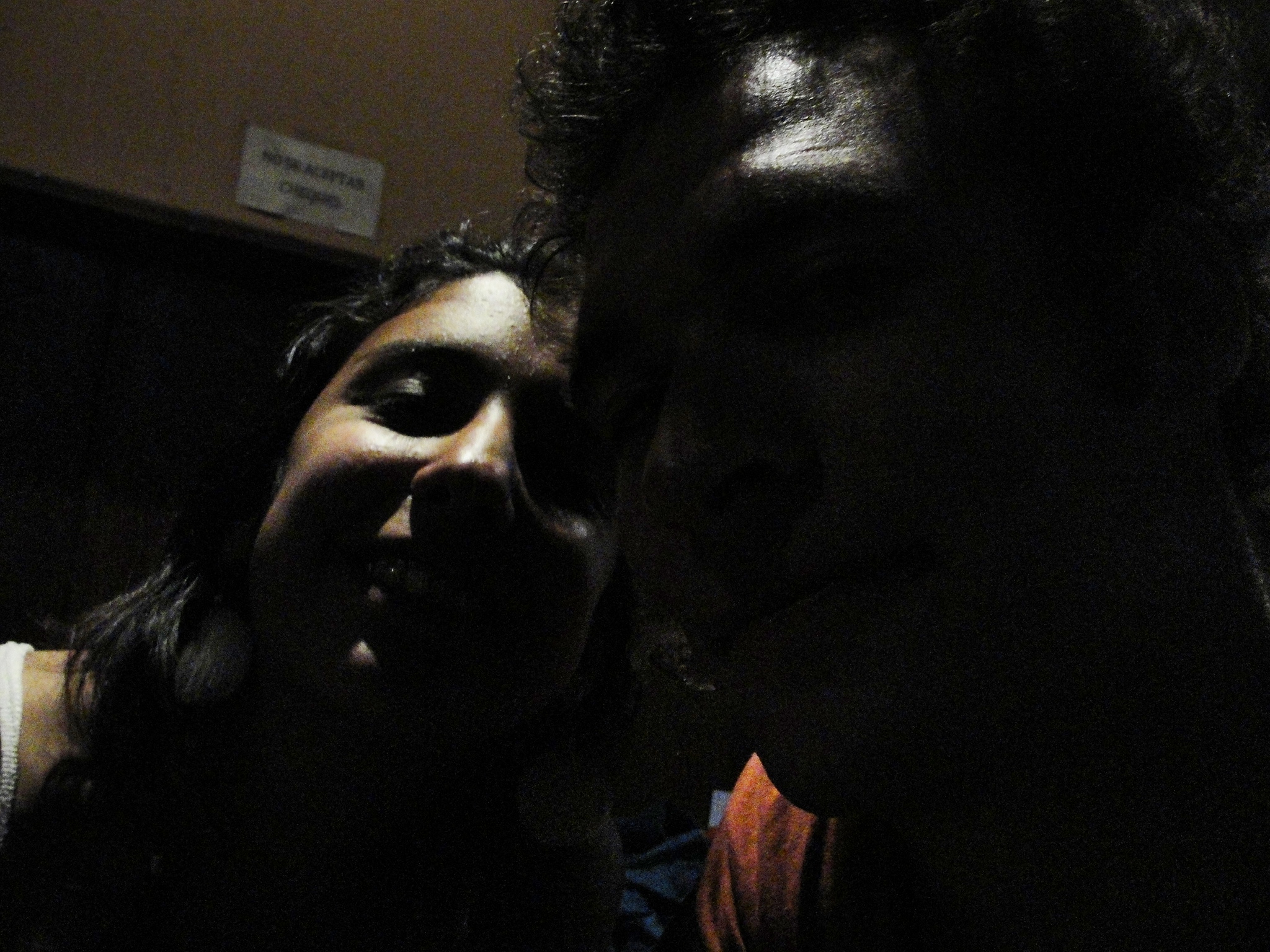 two people posing for the camera in a dark room