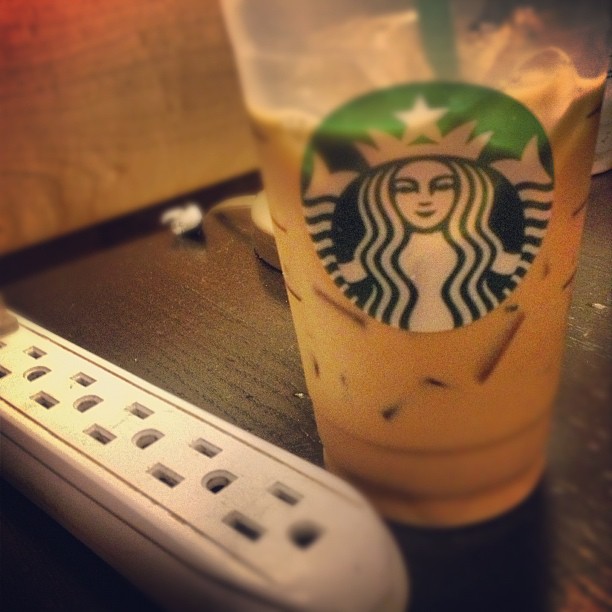 a starbucks drink is sitting on a desk next to a remote control