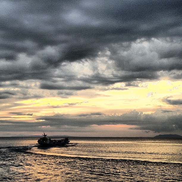 a boat that is in the water under some cloudy skies