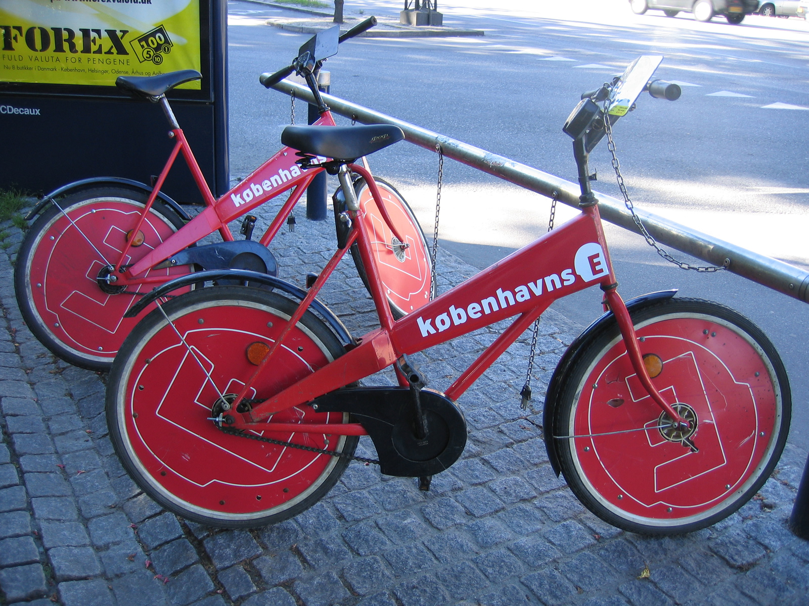 the red bicycle is parked beside the pole and road