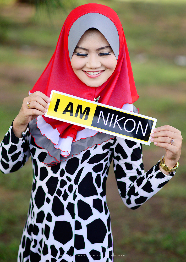 a woman with a red scarf and dress holding up a sign that reads, i am nikn