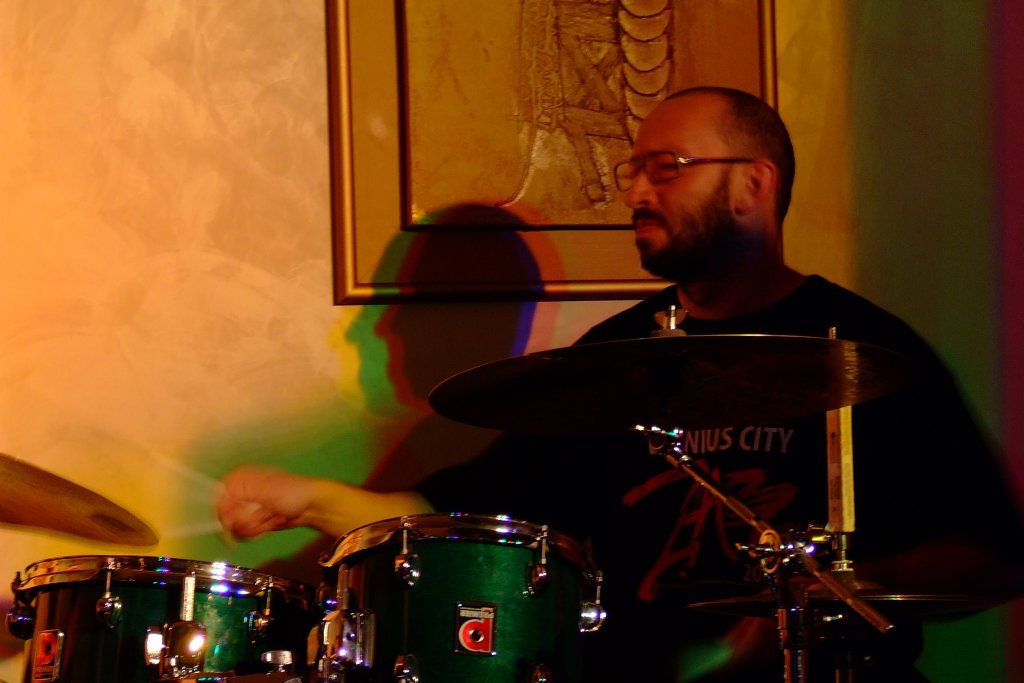 a man with glasses playing the drums in a band