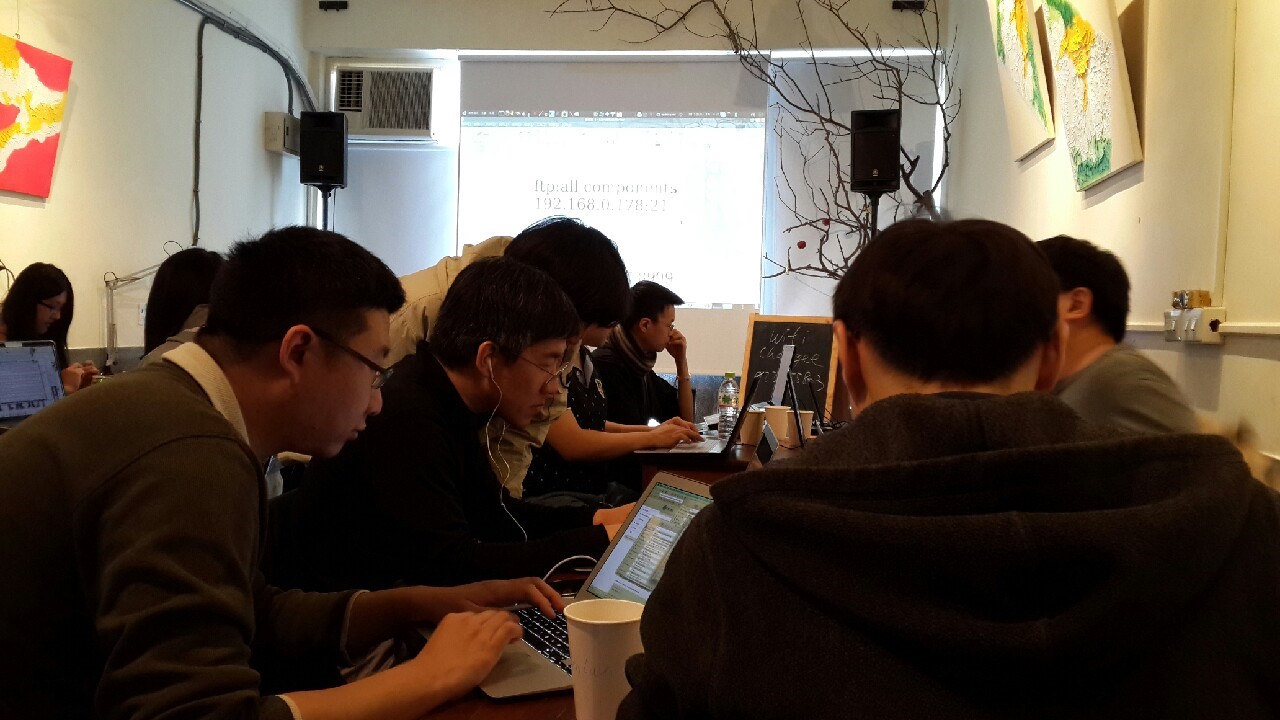 a group of people sitting around at a table with electronic devices