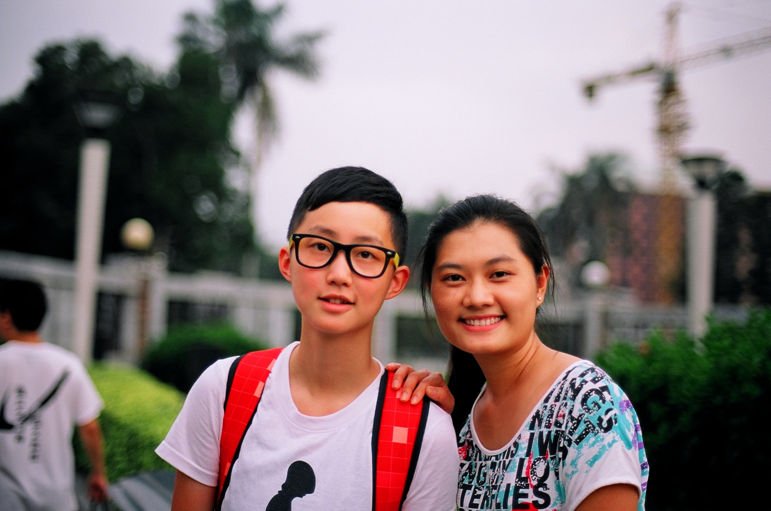 two students with glasses and a backpack smile