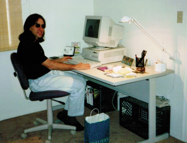 a woman sits at a white table with a monitor and other office equipment