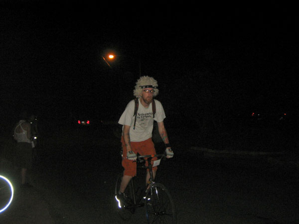 man riding bike at night wearing fuzzy cap and light up headband