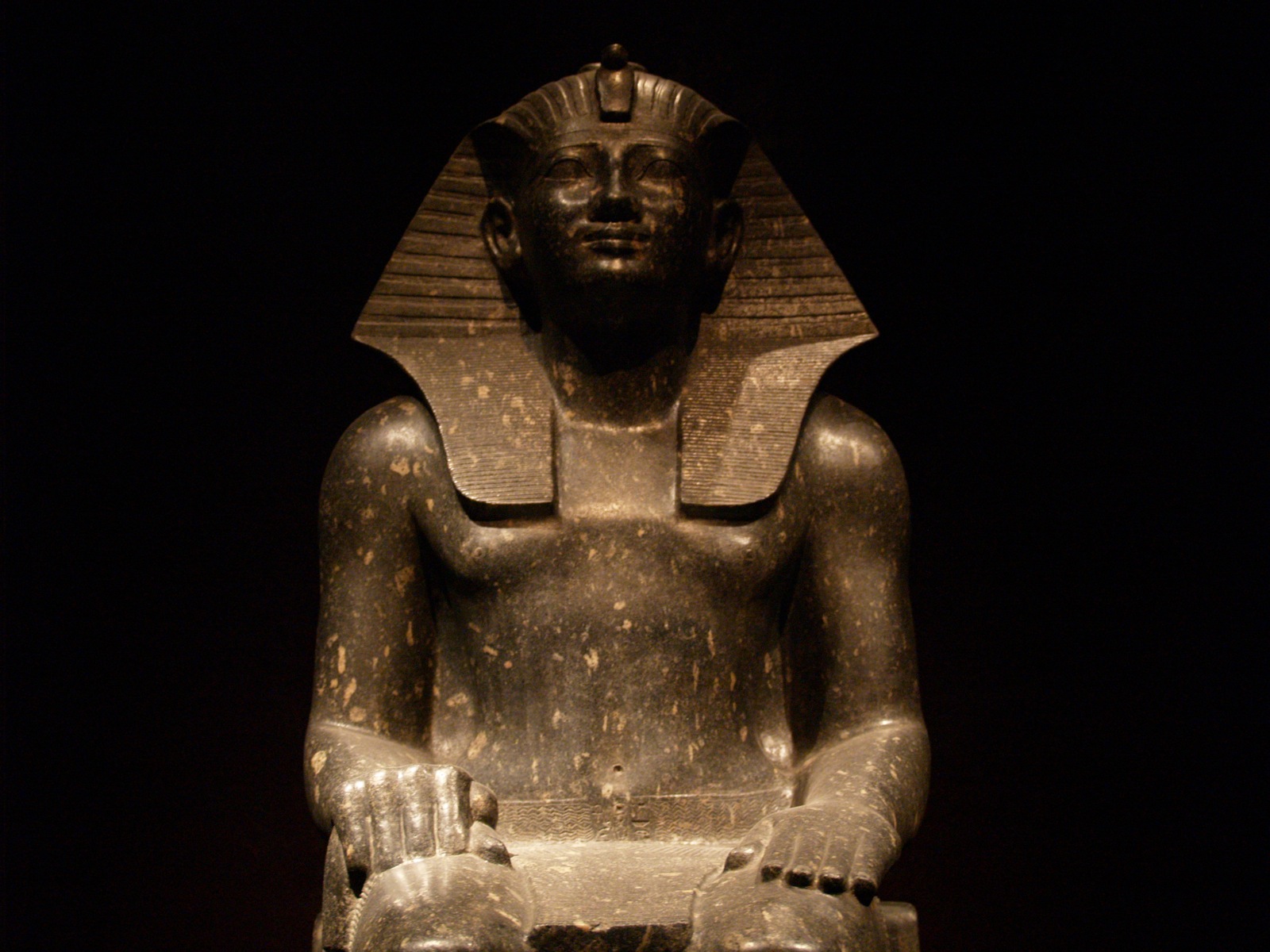 an ancient statue is shown against a dark background