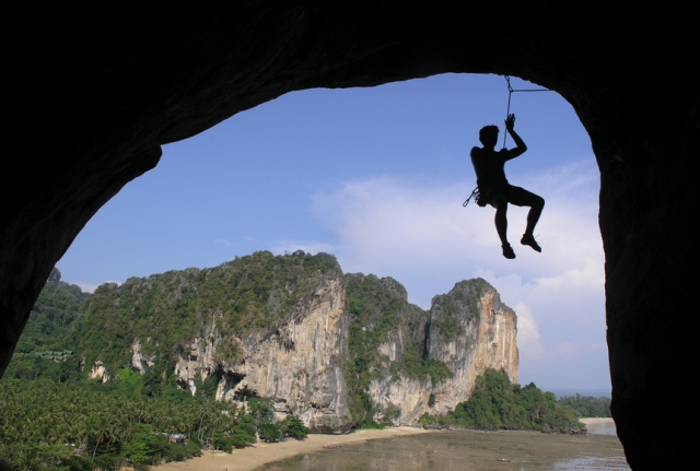 a man hanging on to an artificial rope suspended over a river