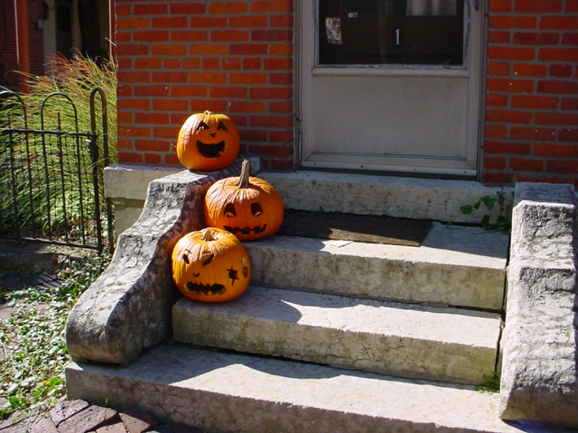 four carved pumpkins on a front porch for halloween
