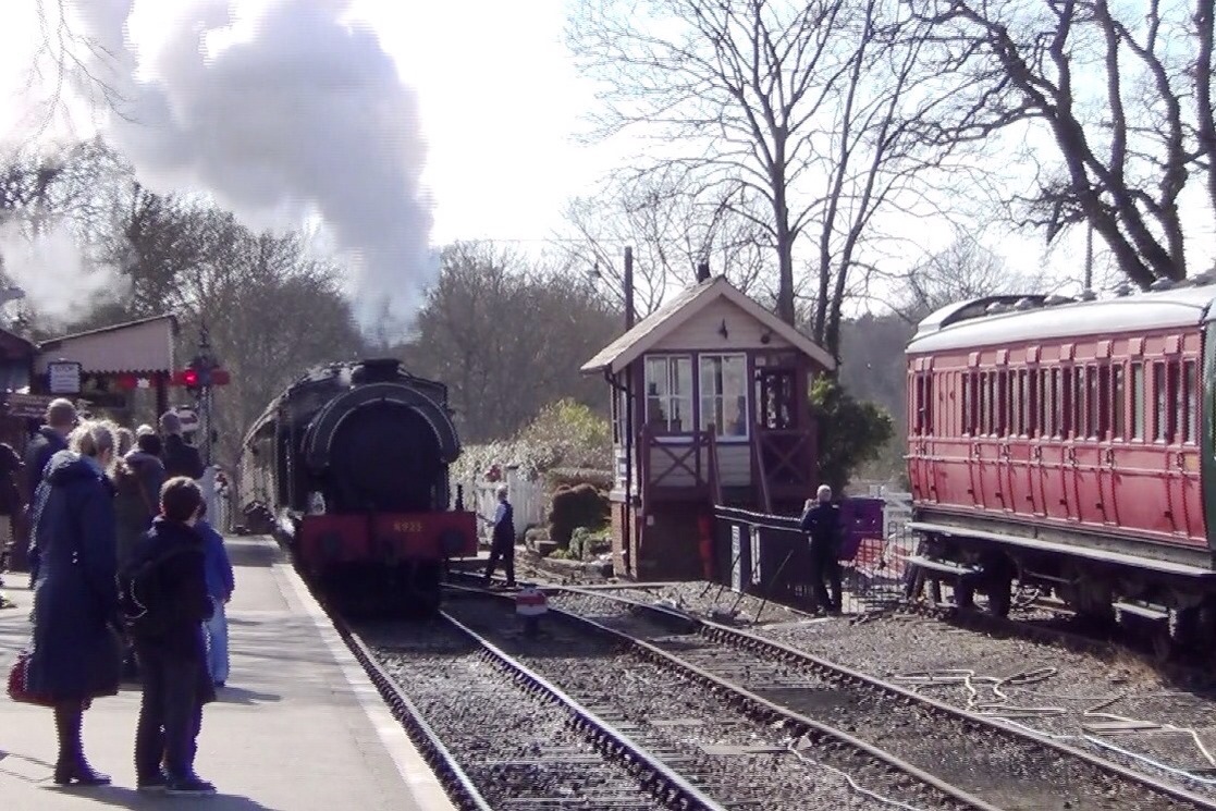 a group of people at a train station watching a train pass by