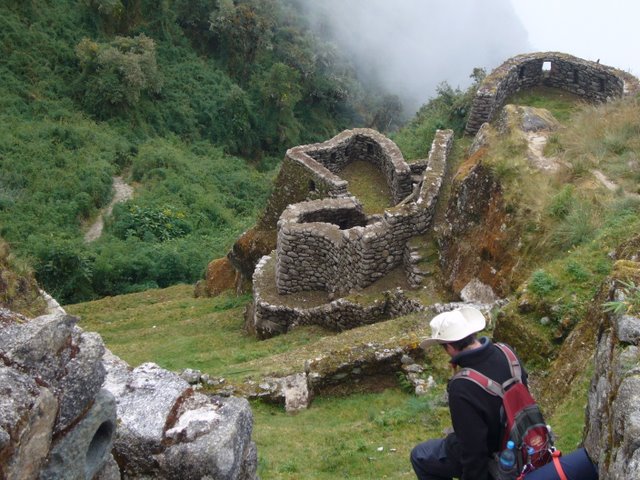 man in helmet looking down at some ruins and valleys
