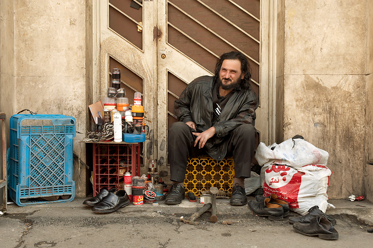 man sitting outside with various items on ground next to him