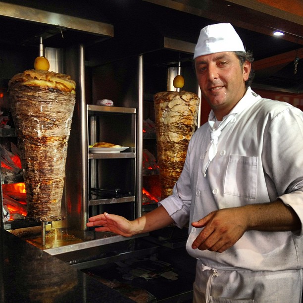 a chef poses next to some bread on a rack