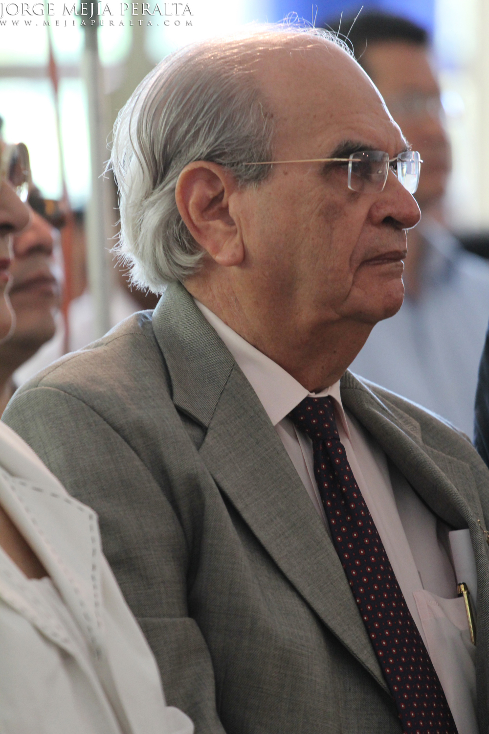 a close up view of an elderly man wearing glasses and a suit
