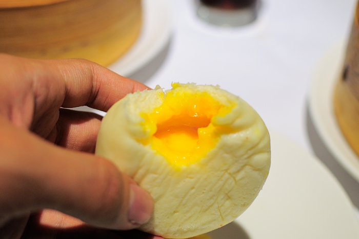 a hand holds an open deviled egg with orange and white topping