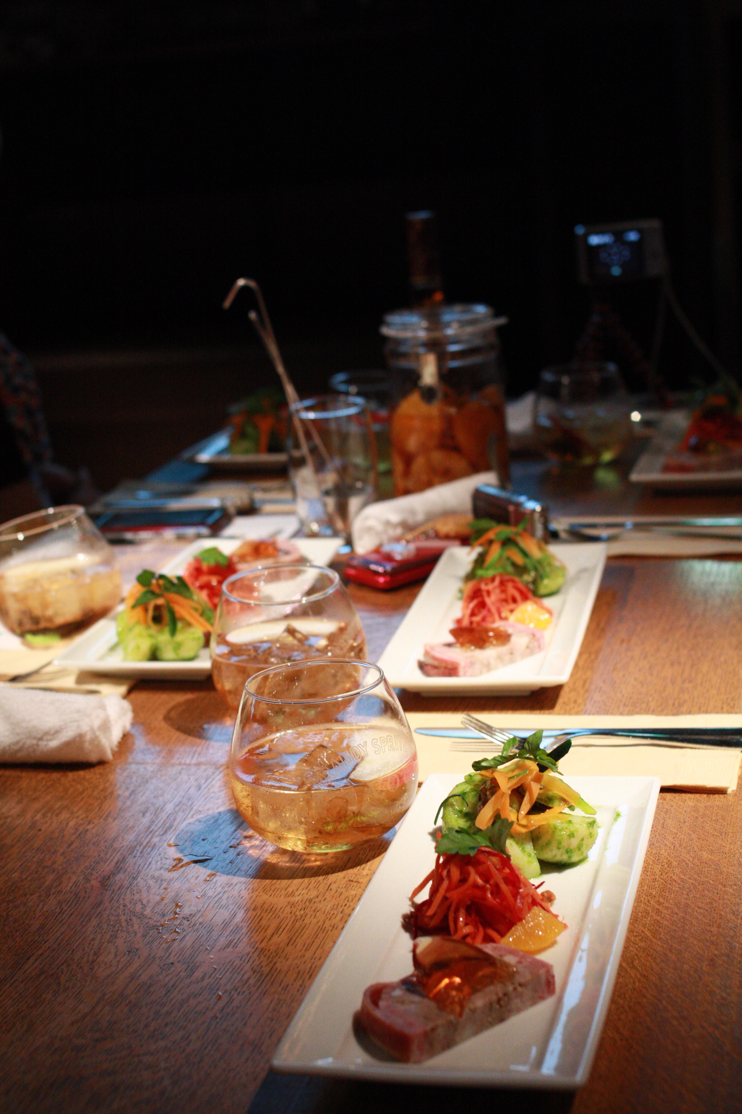 several plates are sitting on a table with wine glasses