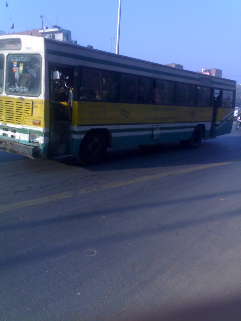 an abandoned yellow and green bus sits in the street