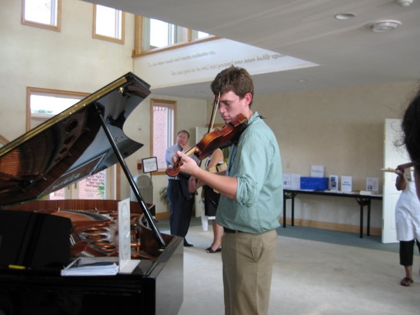 a man plays a violin on top of a piano