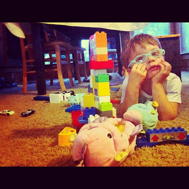 a small boy laying on the floor with toys
