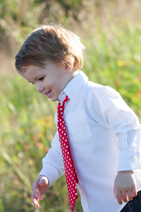 a small boy dressed in white shirt and red tie