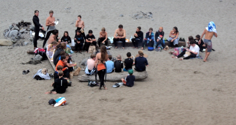 there are many people sitting in a circle on the sand