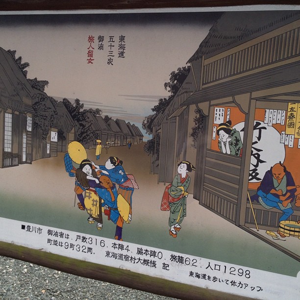 a sign in a japanese town depicting people sitting on a bench