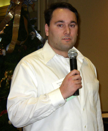 man holding a microphone standing in front of a christmas tree