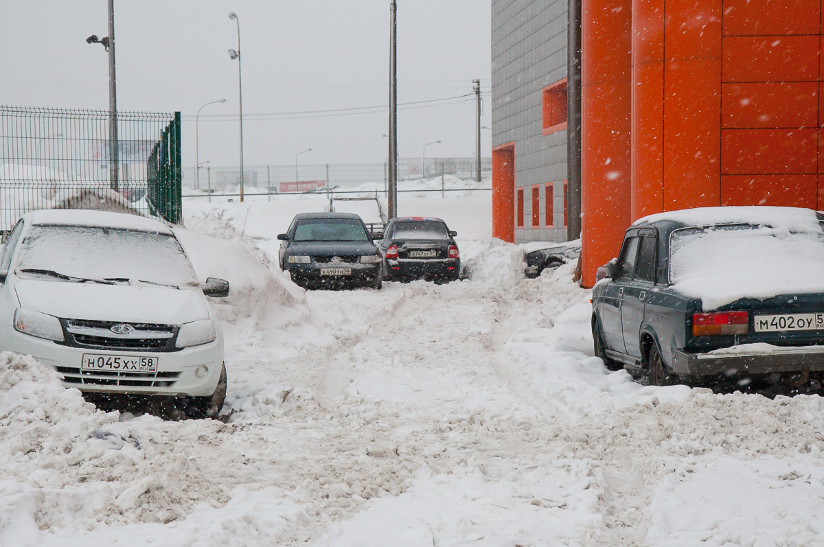 cars are parked on the snow covered road