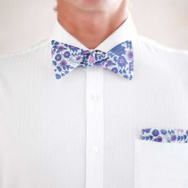 a man wearing a flowered bow tie, white shirt and a blue pocket square