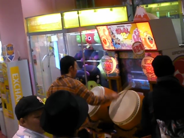people standing around an arcade machine while playing with items
