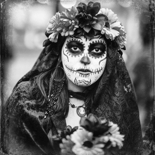 a woman with her face painted white and wearing a large floral crown