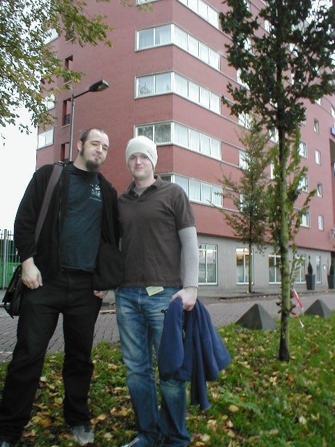 two young men standing next to each other in front of a building