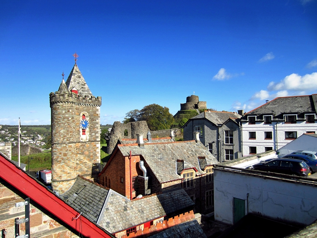 a castle sitting above some city buildings with cars parked