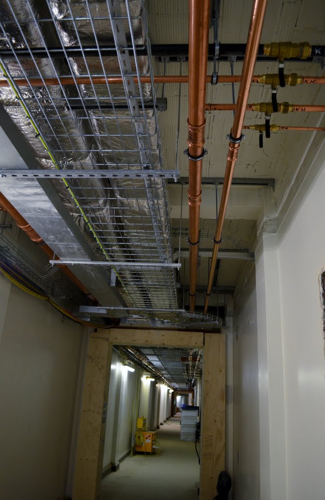 a hallway has pipes and air ducts on the ceiling