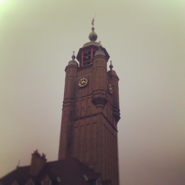 a clock tower on a cloudy day above a rooftop