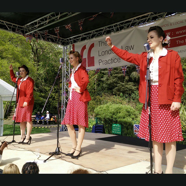 three girls singing in red suits while standing on stage