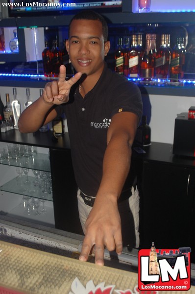 a man standing at a bar making the peace sign