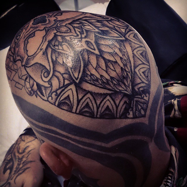 a person with his head covered in tattoos and a headpiece