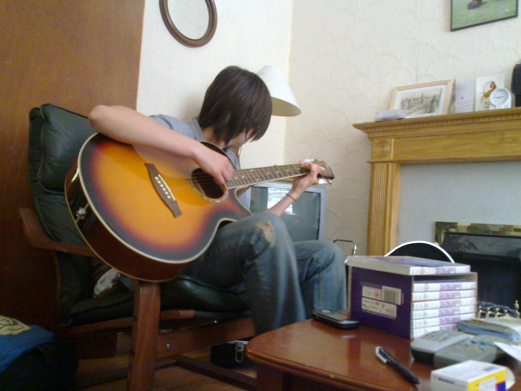 a man sitting in a chair while playing a guitar